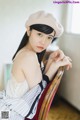 A woman sitting on a chair wearing a beret.