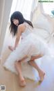 A woman in a white dress sitting on a white rug.