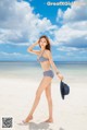 A woman in a bikini standing on a beach.