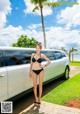 A woman in a black bikini standing next to a white limousine.