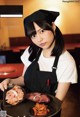 A woman in an apron holding a tray of food.