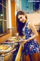 A woman in a floral dress holding a tray of food.