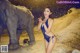 A woman in a blue bathing suit standing next to an elephant.