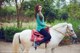 A woman riding on the back of a white horse.