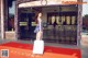 A woman standing in front of a hotel with a suitcase.