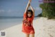 A woman in a red dress standing on a beach.