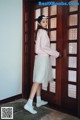 A young woman standing in front of a wooden door.