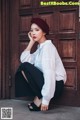 A woman sitting on the ground in front of a wooden door.