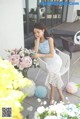 A woman sitting on a white chair next to a bunch of flowers.