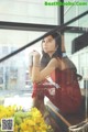 A woman in a red dress sitting on a window sill.