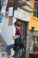 A woman is walking down the street carrying a bag.