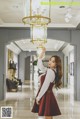 A woman in a red dress holding a chandelier in a hallway.