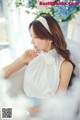 A woman in a white dress sitting on a bed.