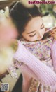 A woman in a pink sweater is holding a pink scarf.