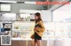 A woman standing in front of a counter in a bakery.