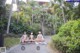 A group of naked women sitting on a path in front of a building.