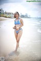 A woman in a blue and white bikini standing in the water.