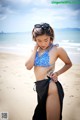 A woman in a blue and white bikini standing on a beach.