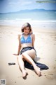 A woman in a bikini sitting on the beach.