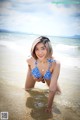 A woman in a blue and white bikini standing in the water.