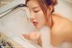 A woman is taking a bath in a bathtub with foam.