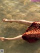 A woman in a red dress floating in the water.