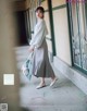 A woman in a gray dress is walking down a hallway.