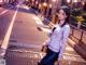 A woman standing on the side of a street at night.