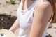 A woman wearing a white tank top and a straw hat.