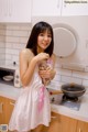 A woman in a white dress holding a jar of flowers.