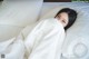 A woman laying in bed under a white blanket.