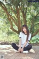 A woman sitting on a wooden deck in front of a tree.