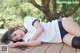 A woman laying on a wooden deck in a white shirt and black shorts.