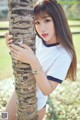 A young woman leaning against a palm tree in a park.