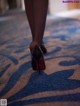 A close up of a woman's legs in high heels on a carpet.