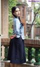 A woman in a blue shirt and black skirt standing on a balcony.