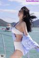 A woman in a white bikini standing on a boat.