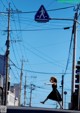 A woman in a black dress and straw hat crossing the street.