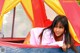 A young woman laying in a tent with a teddy bear.