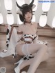 A woman in a cow costume sitting on the floor.