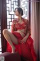 A woman in a red dress sitting on a window sill.