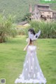 A woman in a white dress standing in a field.