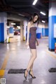 A woman in a purple dress is standing in a parking garage.