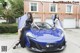 A couple of women sitting on top of a blue car.