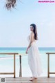 A woman in a white dress standing on a wooden deck.