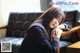 A woman in a school uniform sitting on a couch.