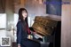 A woman in a school uniform sitting at a piano.