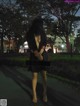 A woman in a black dress is walking down the street.