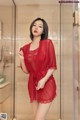 A woman in a red robe standing in a bathroom.