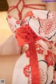 A woman in a red and white kimono is sitting on a bed.